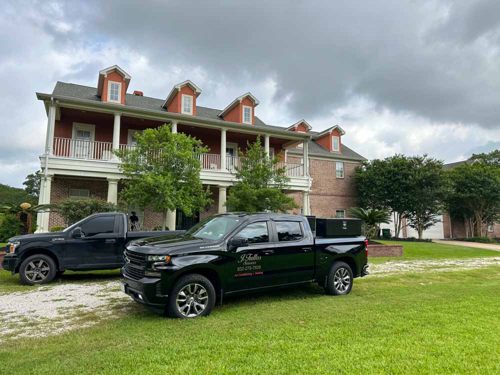 Two black service trucks parked in front of a large residential home, ready to provide HVAC services.